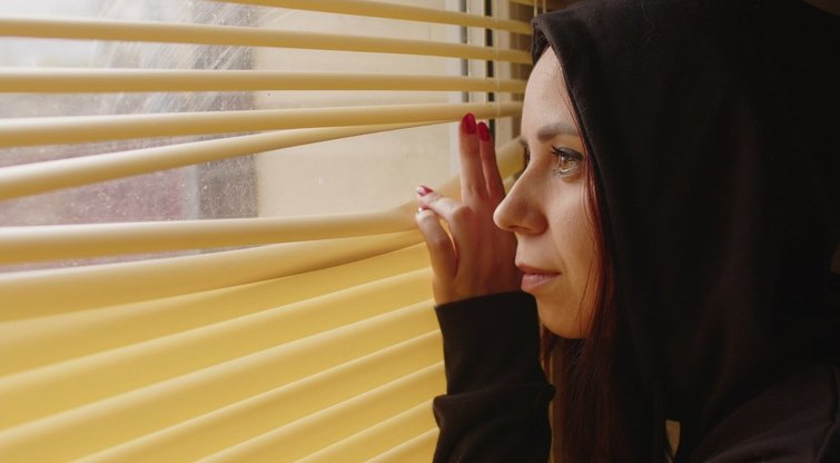 Moteris žiūri pro langą, asociatyvi nuotrauka (nuotr. 123rf.com)
